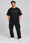 Modelo usando camiseta oversized preta com estampa branca O caminho dEle é melhor
